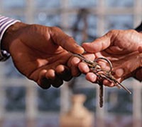 Foto: primo piano di due mani di uomini che si scambiano un mazzo di chiavi